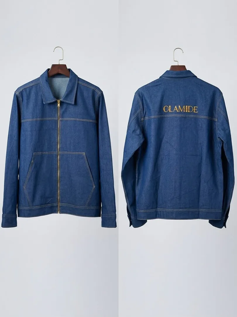 Blue denim jacket shown from the front and the back, with the name OLAMIDE embroidered in gold across the upper back