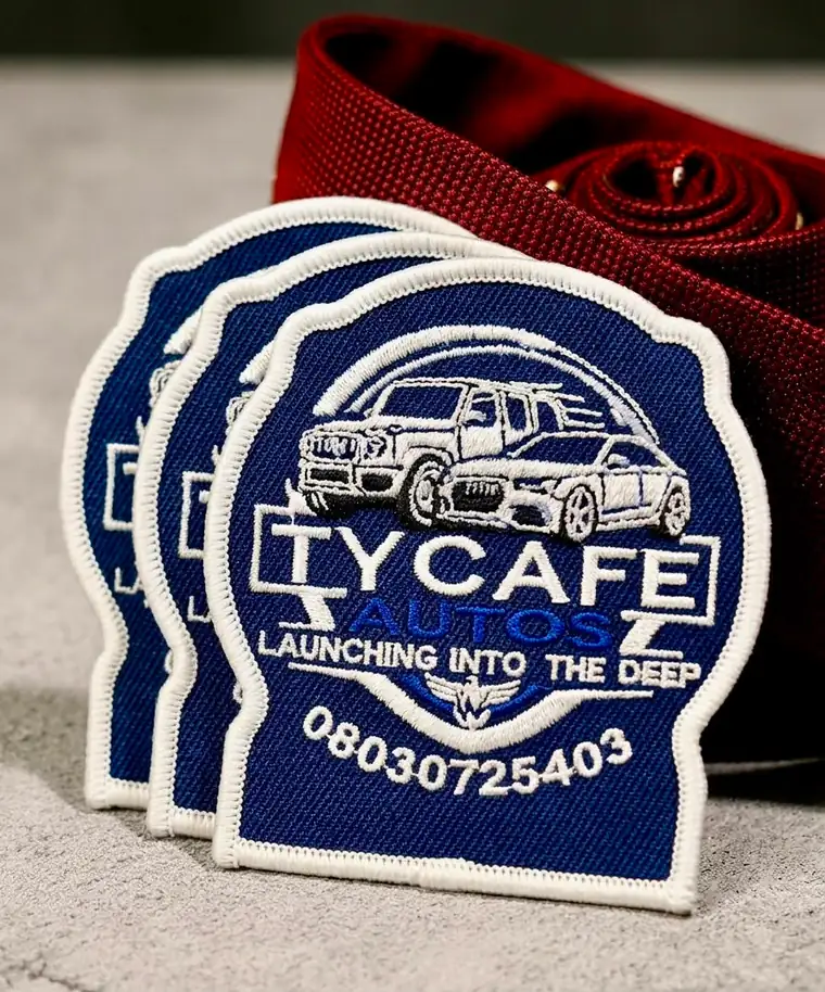 Three navy and white embroidered Tycafe Autos logo patches